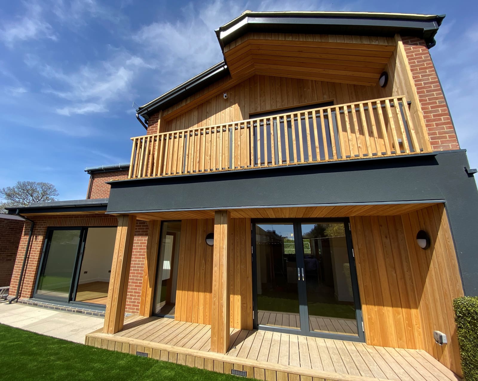 London home with timber cladding, brick and a timber balcony